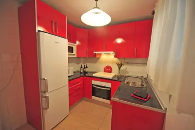 a kitchen with red cabinets and a white refrigerator at Apto Terrazas 3 Rooms 2 baños Cabildo Playa Parking in Sanlúcar de Barrameda