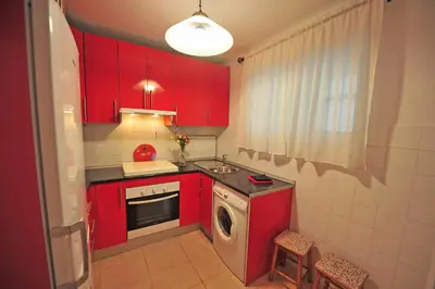 a kitchen with red cabinets and a washing machine at Apto Terrazas 3 Rooms 2 baños Cabildo Playa Parking in Sanlúcar de Barrameda