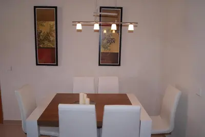a dining room with a wooden table and white chairs at Costa Ballena Cómodo Bajo con Piscina, Patio y 3 Dormitorios Parking free in Rota