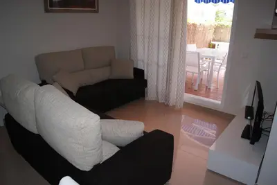 a living room with a couch and a chair at Costa Ballena Cómodo Bajo con Piscina, Patio y 3 Dormitorios Parking free in Rota