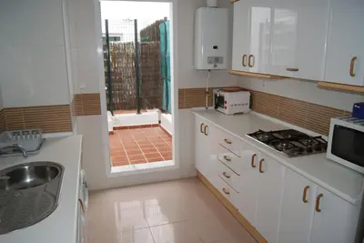 a kitchen with white cabinets and a sink and a window at Costa Ballena Cómodo Bajo con Piscina, Patio y 3 Dormitorios Parking free in Rota