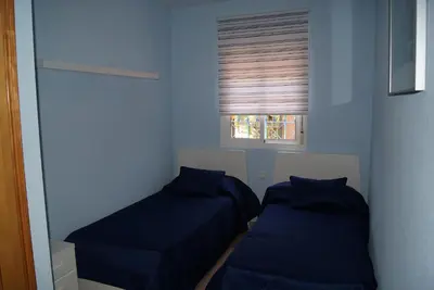 two beds in a small room with a window at Costa Ballena Cómodo Bajo con Piscina, Patio y 3 Dormitorios Parking free in Rota