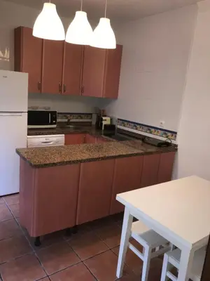 a kitchen with brown cabinets and a white table at MARIÑIGUEZ APARTAMENT. in Jerez de la Frontera