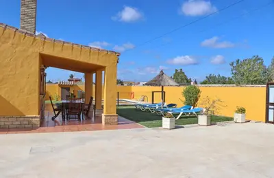 a patio with a table and chairs and a yellow wall at Casa Calas Boliña in Roche