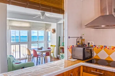 a kitchen with a view of the ocean and a table at Una ventana al mar in Rota