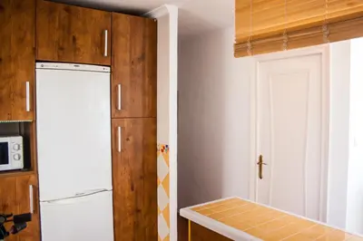 a kitchen with a white refrigerator and a door at Una ventana al mar in Rota