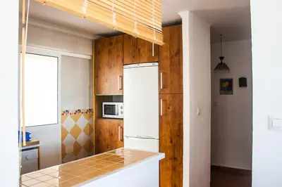 a kitchen with wooden cabinets and a white refrigerator at Una ventana al mar in Rota