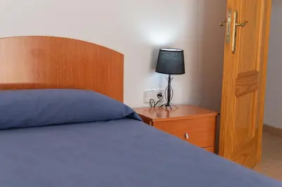 a bedroom with a bed and a lamp on a night stand at La casa de las margaritas in Cádiz