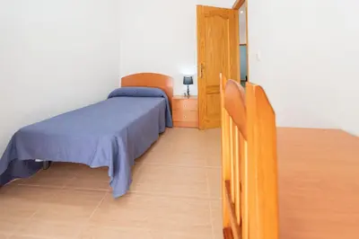 a bedroom with a bed and a wooden floor at La casa de las margaritas in Cádiz
