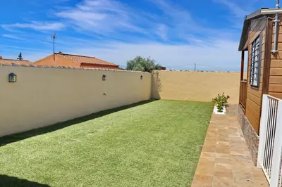 a backyard with a green lawn next to a building at Bungalow con piscina privada in Conil de la Frontera