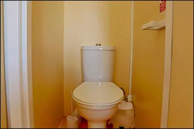 a white toilet in a bathroom with yellow walls at Bungalow con piscina privada in Conil de la Frontera