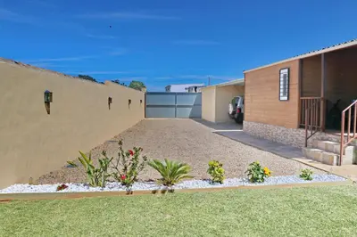 a house with a fence and a yard with flowers at Bungalow con piscina privada in Conil de la Frontera