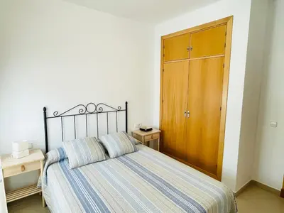 a bedroom with a bed and a wooden cabinet at Ático Premium Conil con 2 terrazas, parking, piscina, Aire Ac y WIFI -SOLO FAMILIAS Y PAREJAS- in Conil de la Frontera