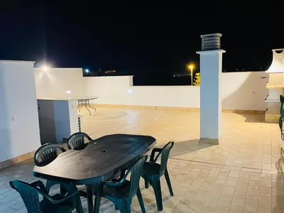 a table and chairs on a patio at night at Ático Premium Conil con 2 terrazas, parking, piscina, Aire Ac y WIFI -SOLO FAMILIAS Y PAREJAS- in Conil de la Frontera