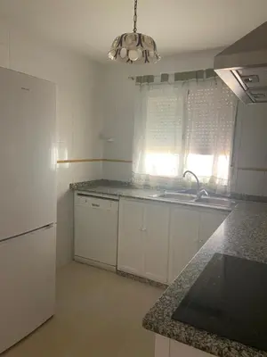 a kitchen with white cabinets and a sink and a window at Victoria Chipiona Unifamiliar in Chipiona