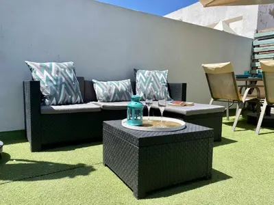 a table with chairs and an umbrella on a patio at Fantástico ático en el casco antiguo en a la playa in Cádiz