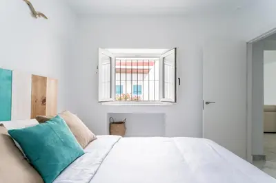 a bedroom with a white bed and a window at Fantástico ático en el casco antiguo en a la playa in Cádiz