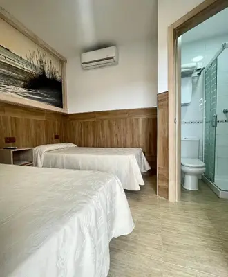 a hotel room with two beds and a toilet at Hostal Noli in Chiclana de la Frontera