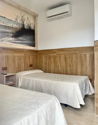 a room with two beds and a air conditioner at Hostal Noli in Chiclana de la Frontera