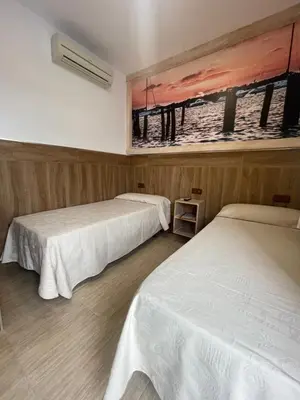 a room with two beds and a painting on the wall at Hostal Noli in Chiclana de la Frontera