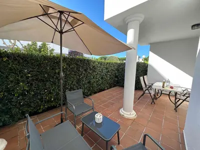 a patio with an umbrella and chairs and a table at Novo Sancti Petri Atardecer Planta baja in Chiclana de la Frontera