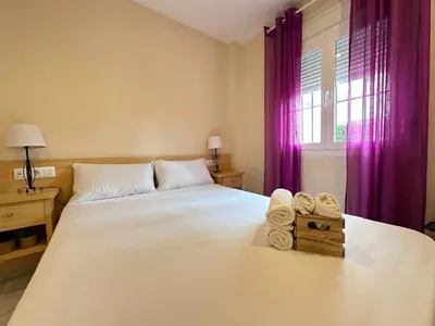 a bedroom with a large white bed with purple curtains at Novo Sancti Petri Atardecer Planta baja in Chiclana de la Frontera