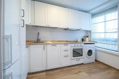 a kitchen with white cabinets and a washer and dryer at Apartamento Albatro´s suite in Cádiz