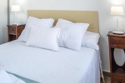a white bed with white pillows and two lamps at Apartamento Albatro´s suite in Cádiz