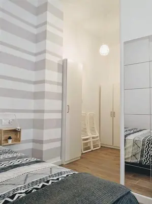 a bedroom with a striped wall with two beds and a mirror at Los Patios de la Caleta in Cádiz