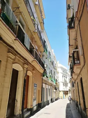 an alley between two buildings with people walking down the street at Sopranis del MAR Apartamento centro Cádiz, junto playa y estación in Cádiz
