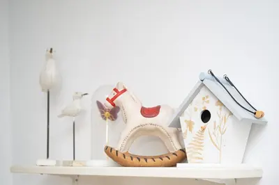 a white shelf with a birdhouse and a toy house at Sol y Vida, Apartamentos Living Sur in Sanlúcar de Barrameda