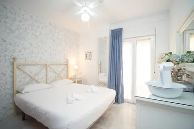 a white bedroom with a bed and a sink at Sol y Vida, Apartamentos Living Sur in Sanlúcar de Barrameda