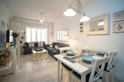 a kitchen and living room with a table and chairs at Sol y Vida, Apartamentos Living Sur in Sanlúcar de Barrameda
