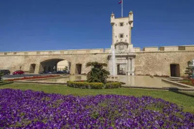 a building with a tower with a bunch of purple flowers at Tu Rincón Gaditano PLAYA y WIFI Grupo AC Gestion in Cádiz
