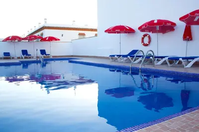 a swimming pool with umbrellas and chairs and a pool at Villa la Dehesa in Conil de la Frontera