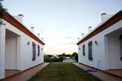 a courtyard between two white buildings with a yard at Villa la Dehesa in Conil de la Frontera