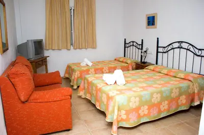 a hotel room with two beds and a chair at Villa la Dehesa in Conil de la Frontera