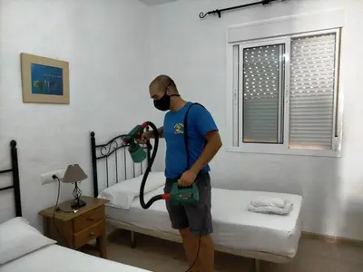 a man with a mask and a vacuum cleaner in a bedroom at Villa la Dehesa in Conil de la Frontera