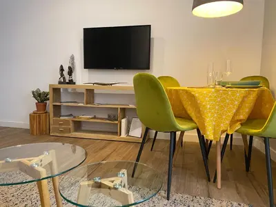 a dining room with a table with chairs and a television at Charito 18 in Cádiz