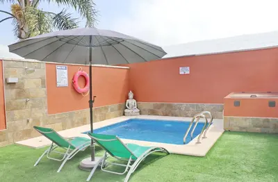 a swimming pool with two chairs and an umbrella at Chalet Sultan con piscina in Conil de la Frontera