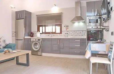 a kitchen with stainless steel appliances and a table at Chalet Sultan con piscina in Conil de la Frontera