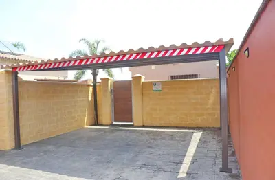a garage with a red awning next to a building at Chalet Sultan con piscina in Conil de la Frontera