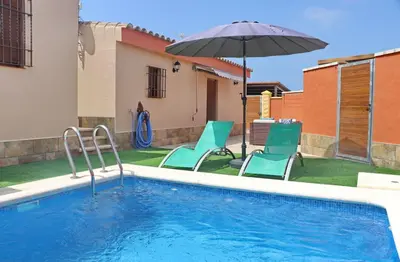 a swimming pool with two chairs and an umbrella at Chalet Sultan con piscina in Conil de la Frontera