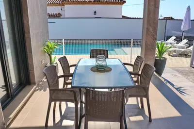 a blue table and chairs on a balcony with a pool at Chalet moderno con pisicina in Conil de la Frontera