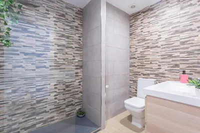 a bathroom with a toilet and a stone wall at Luxe Vista Histórico 5 rooms 4 baños in Jerez de la Frontera