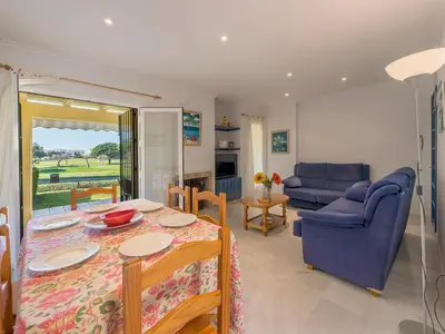 a living room with a table and a blue couch at Holiday Home Brisamar - Novo Sancti Petri by Interhome in Chiclana de la Frontera