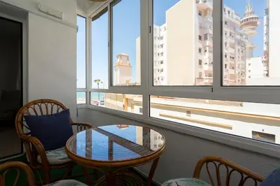 a room with a table and chairs and windows at Cádiz Beach & Kids - free parking - sea views in Cádiz