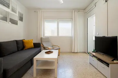 a living room with a couch and a tv at Cádiz Beach & Kids - free parking - sea views in Cádiz