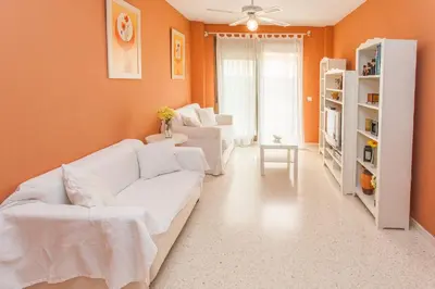 a living room with white furniture and orange walls at Apartamento Centro Jerez in Jerez de la Frontera