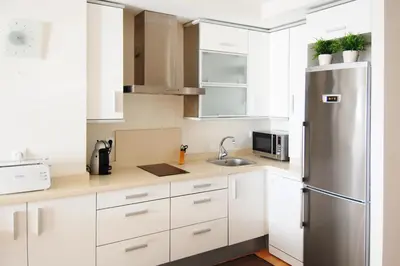 a kitchen with white cabinets and a stainless steel refrigerator at Apartamento Playa Victoria Cadiz in Cádiz